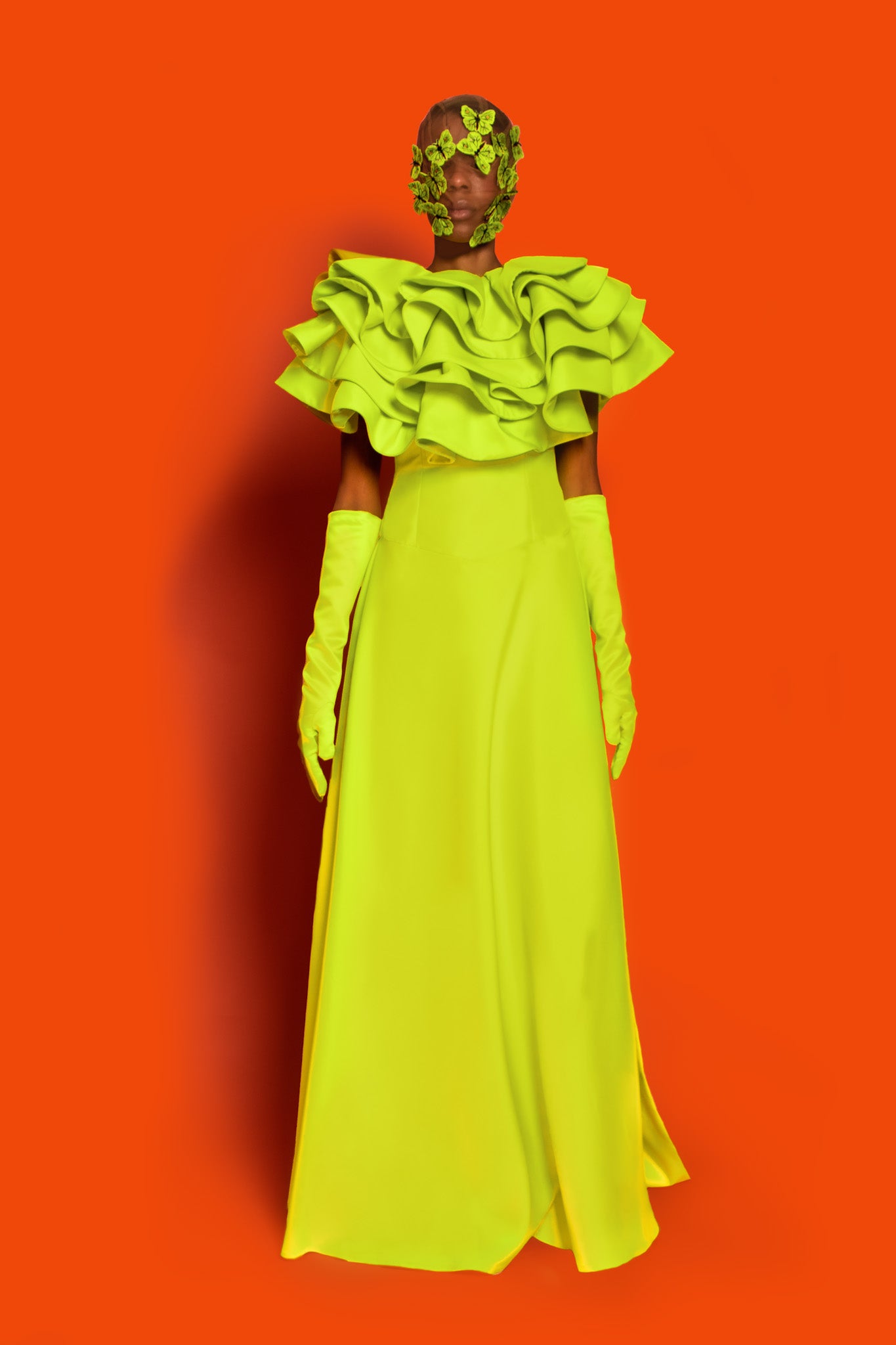 A lime green dropped waist maxi dress features exploded ruffles on the chest to shoulder and back with a buttcape.