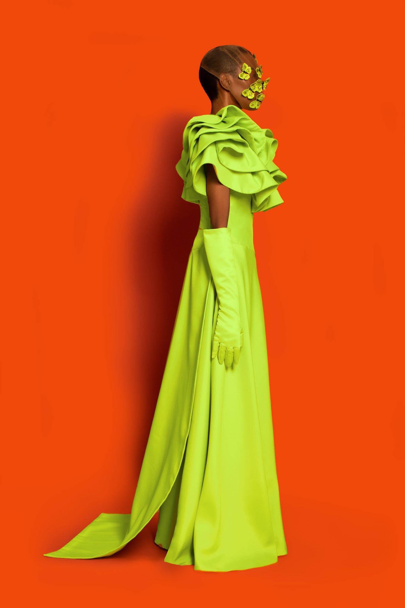 A lime green dropped waist maxi dress features exploded ruffles on the chest to shoulder and back with a buttcape.